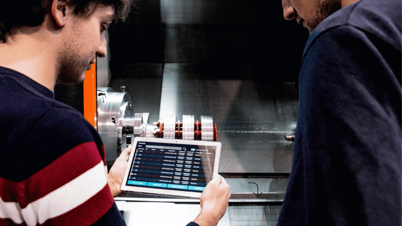 Operario industrial consultando software de gestión de taller en tablet junto a maquinaria CNC – soluciones digitales ZITU para la industria