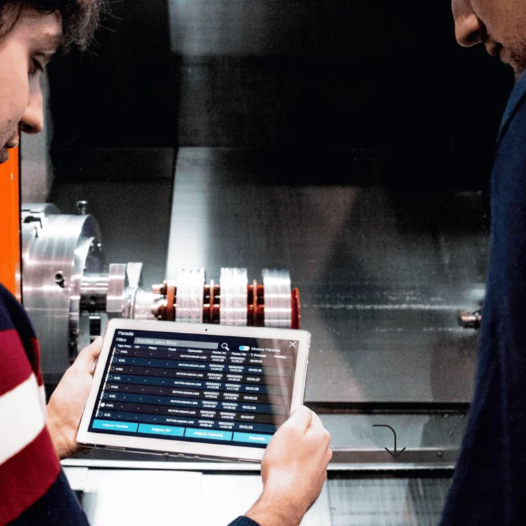 Operario industrial consultando software de gestión de taller en tablet junto a maquinaria CNC – soluciones digitales ZITU para la industria